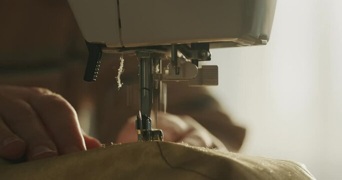 A woman sews bed linen on a sewing machine, close-up.