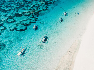 Blue ocean and beach with fishing boats in tropics. Aerial view.