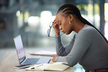 Mental health, businesswoman with headache and laptop at her desk in modern workplace office....