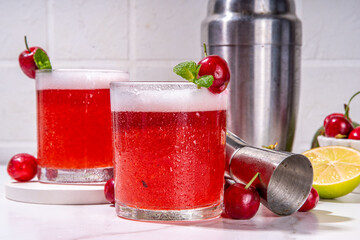 Cherry and lime alcoholic booze cocktail, sweet summer alcohol drink with cherry juice, vodka and fruit lime cherry garnish