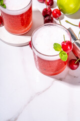 Cherry and lime alcoholic booze cocktail, sweet summer alcohol drink with cherry juice, vodka and fruit lime cherry garnish