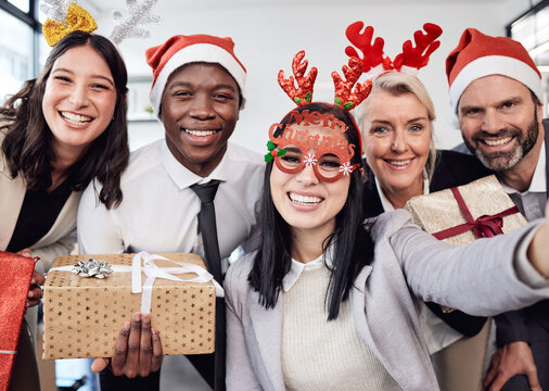 Friends, selfie and business people at christmas party in the office with silly accessories. Diversity, smile and happy corporate colleagues taking picture together with gifts at festive celebration.