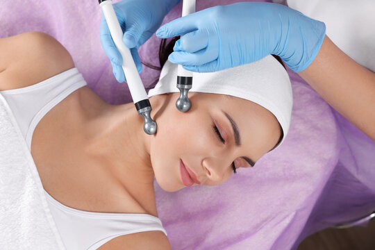 Young woman undergoing cosmetic procedure in beauty salon, top view. Microcurrent therapy