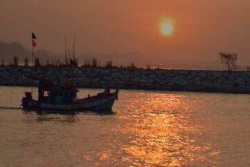 the sun is setting At sea, there are fishing boats passing by.