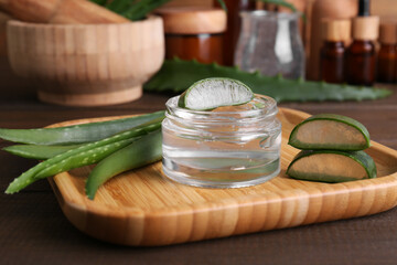 Jar with natural gel and aloe vera leaves on wooden table