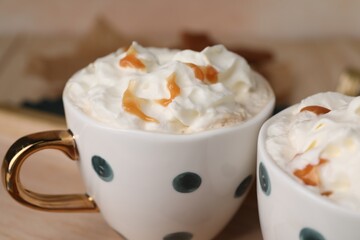 Delicious coffee with whipped cream and caramel syrup in cups, closeup