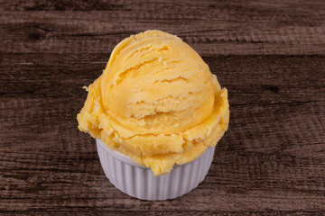 Yellow ice cream served in a white pot. Tasty traditional yellow gelato enjoyed around the world. Close-up photo of food centered in the photo with a 45 degree inclination.