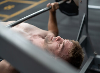 Muscular naked chest man doing deadlift exercise in fitness gym. Young healthy bodybuilder athlete lifting barbell to strength body muscles. Heavy weightlifting is best for biceps workout exercise.