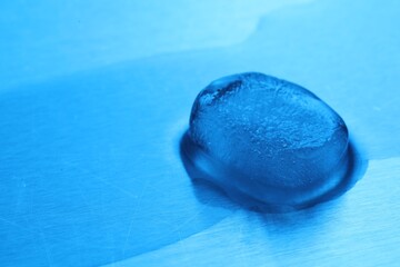 Crystal clear ice cube on light blue background, space for text. Color tone effect