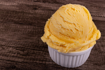 Yellow ice cream served in a white pot. Tasty traditional yellow gelato enjoyed around the world. Close-up photo of food on the right 45 degree tilt.