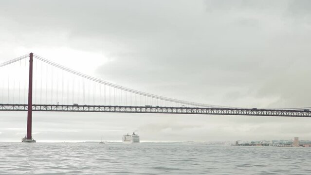 Big ship sails under the bridge in gray weather