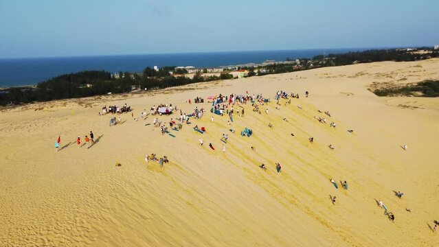 people ride ATVs and boards on the sand dunes