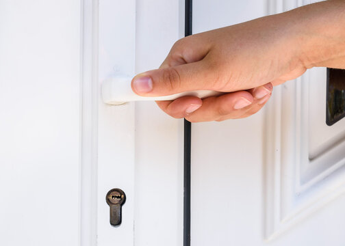 front door. hand holds doorknob on front door PVC
