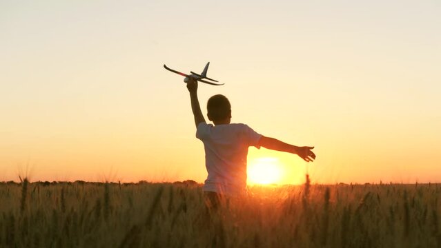 boy teenager child kid runs through field with wheat with toy plane his hands sunset, happy dream family, become pilot, kid wheat plays with toy field, sunset park, spring break, little pilot runs