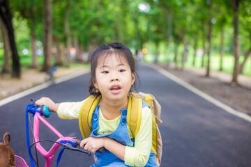 Obraz premium Asian school girl enjoying with bicycle in outdoor park