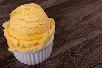 Yellow ice cream served in a white pot. Tasty traditional yellow gelato enjoyed around the world. Close-up photograph with empty space for text on the right.