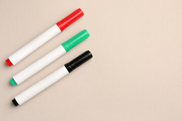 Bright color markers on beige background, flat lay. Space for text