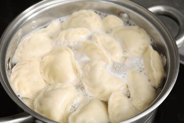 Fototapeta na wymiar Boiling delicious dumplings (varenyky) in pot, closeup