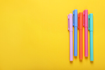 Many colorful markers on yellow background, flat lay. Space for text
