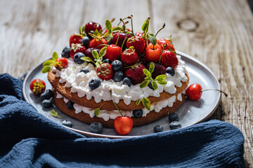 Fresh seasonal layered cake with spring ripe fruit like strawberries, blueberries and cherries....