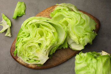 Flat lay composition with fresh green cut and whole iceberg lettuce heads on grey table