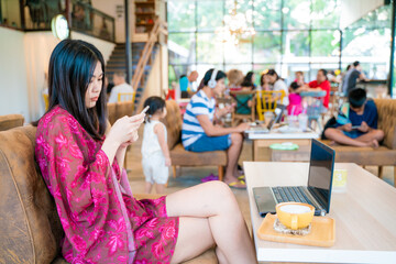 Business asian woman in casual use smartphone sitting in coffee shop