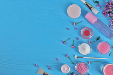 Flat lay composition with homemade cosmetic products and fresh ingredients on light blue wooden table. Space for text