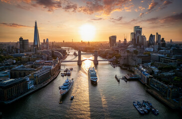 Panoramic aerial view of the skyline of London, England, with a passenger ship crossing under the Tower Bridge during a beautiful sunset