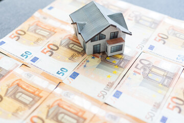 Buying and building a house.House and money. Real estate market. house with gray roof on euro banknotes background. 