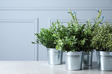 Different artificial potted herbs on light table, space for text
