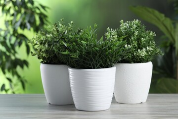 Different artificial potted herbs on white wooden table outdoors