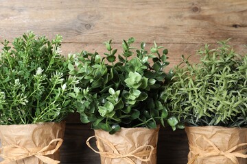 Different artificial potted herbs against wooden background