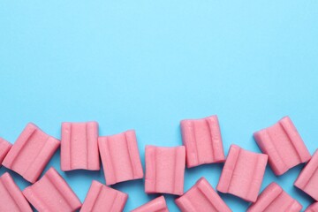 Tasty pink chewing gums on light blue background, flat lay. Space for text
