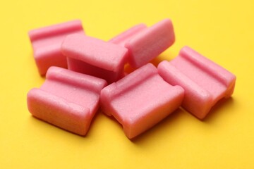 Tasty pink chewing gums on yellow background, closeup