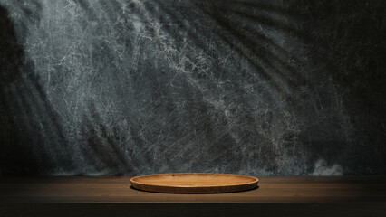 Round wooden plate on the table with dark marble wall background. Light shadow on the wall.