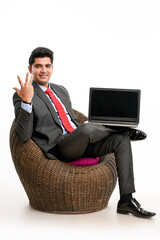 Young indian businessman sitting on chair and showing laptop screen.