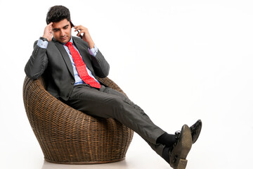 Young indian businessman sitting on chair and talking on smartphone.