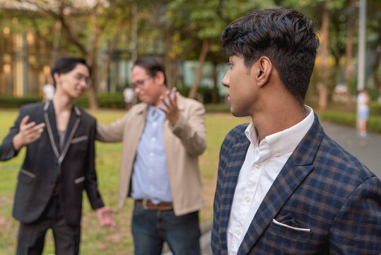 A man sulks after discovering his boss choosing and praising his co-worker while outside. Feeling depressed or jealous. Favoritism and discrimination in the workplace.