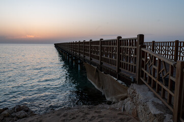 Beginning of a day, orange sunrise over the sea and pier, morning hours, sunset, beautiful romantic atmosphere.