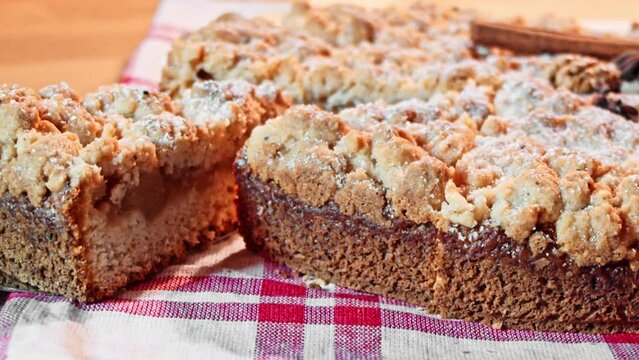 Apple tart with sprinkles arranged on a wooden board with a small white tablecloth with a red pattern