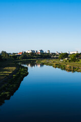 Fototapeta premium Vertical photo of a blue river in the distance with the cityscape. Top view