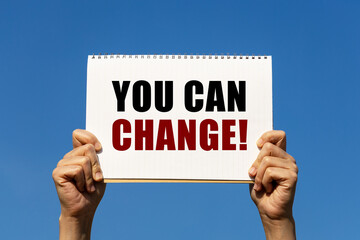 You can change text on notebook paper held by 2 hands with isolated blue sky background. This...