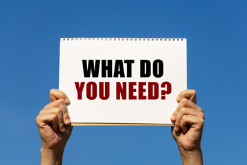 What do you need question text on notebook paper held by 2 hands with isolated blue sky background....