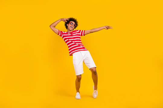 Full length photo of sweet impressed guy dressed red t-shirt dark glasses dancing having fun isolated yellow color background