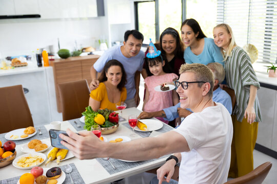 Self-portrait.  Multi-ethnic family. Big family selfie by smartphone while eating food or lunch together and birthday party for grandfather at home