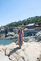Woman traveller is sightseeing and looking at Haedong Yonggungsa Temple in Busan, South Korea. The Chinese text translates "Grand Hall"