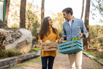 Man and woman carrying crates with freshly harvested organic vegetables