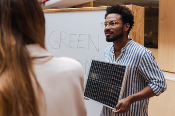 Businessman giving a presentation in office holding solar panel