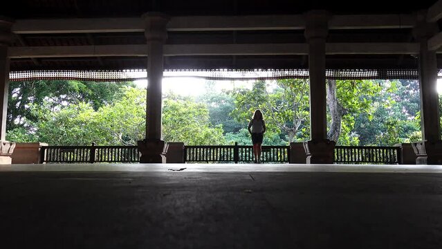 Ubud, Bali, Indonesia A woman walks alone on a large open-air pavilion in a park. 