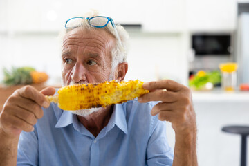 Elderly cuacasian man eating Hot Roasted Corn